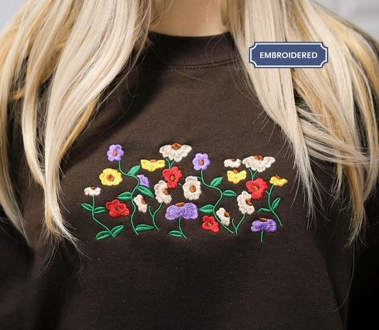 a close-up of a person wearing a brown shirt with a colorful floral embroidered design on the front.