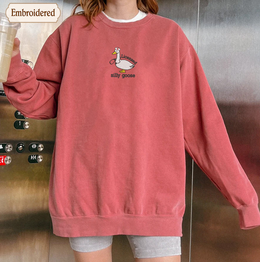 A person wearing a red sweatshirt with a cartoon duck and the text "silly goOSE" printed on it.