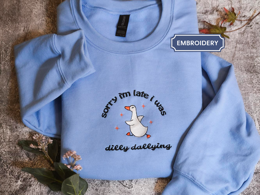 A light blue sweatshirt with a humorous text and graphic design printed on it.