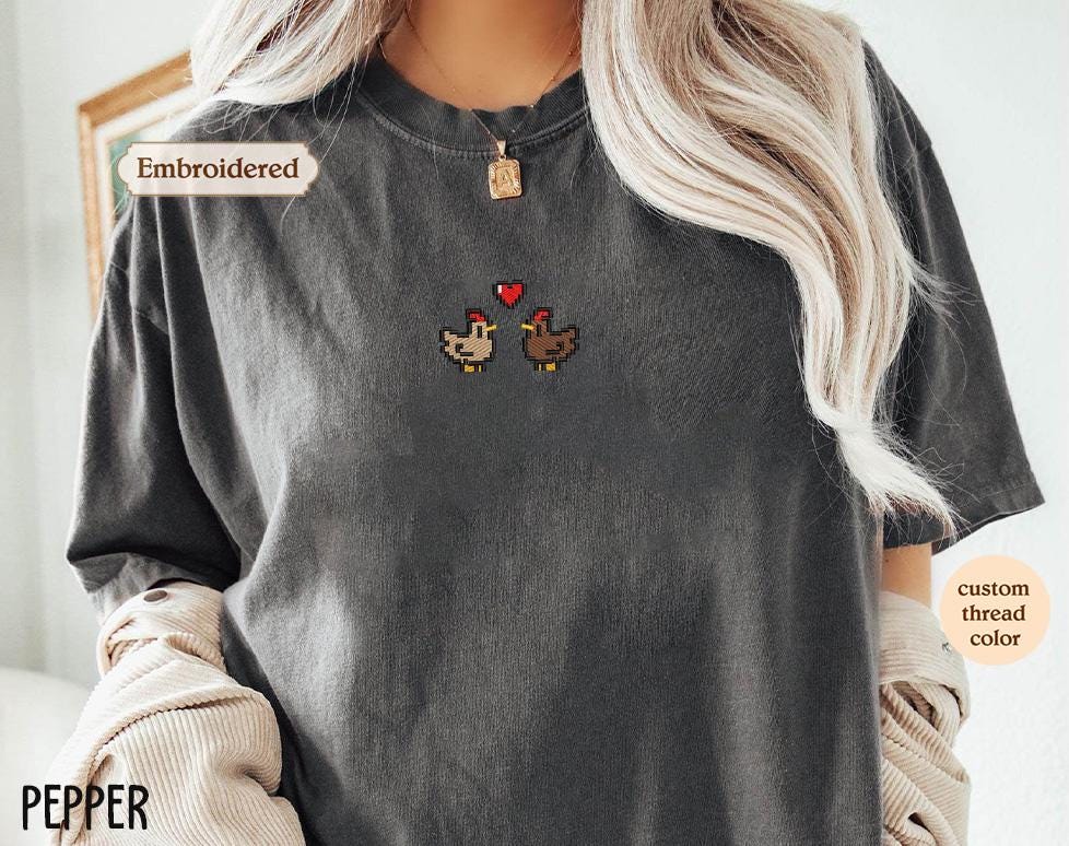 a woman wearing a gray t - shirt with two chickens on it