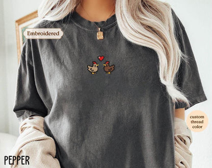 a woman wearing a gray t - shirt with two chickens on it