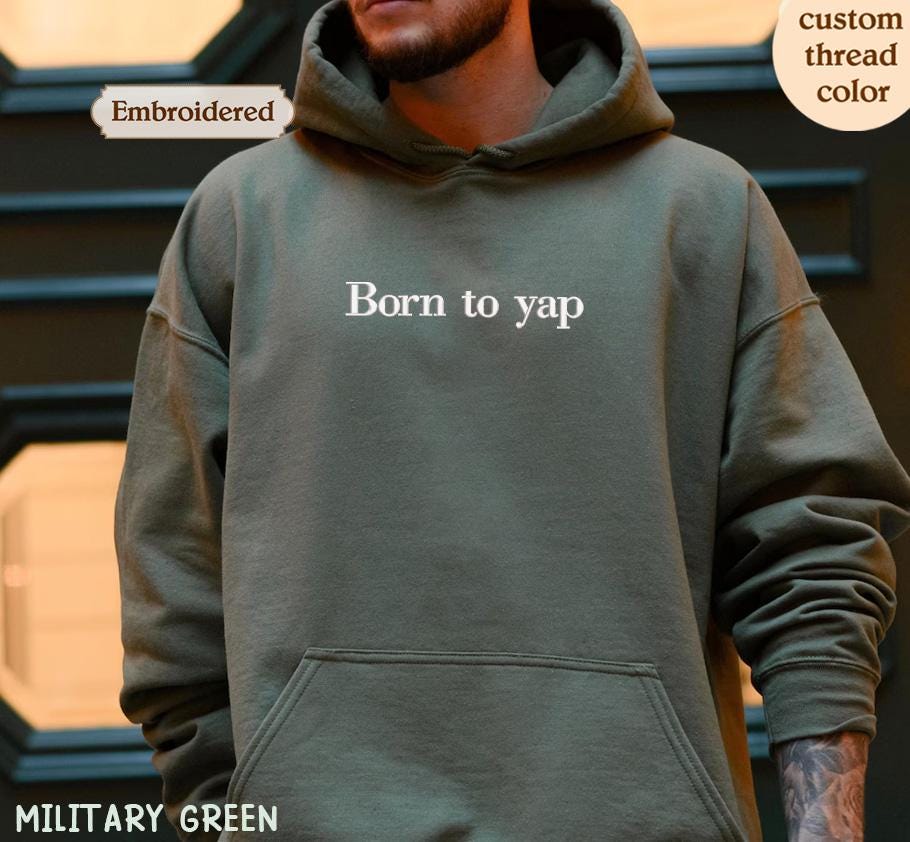 a man wearing a military green hoodie that says born to yap