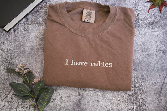 a brown t-shirt with the text "I haverabies" printed on it, along with some leaves and a small plant.
