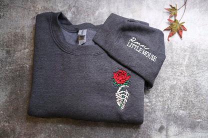 A gray sweatshirt with a red rose embroidered on the front and the text "Run LITTLE MOUSE" printed on the sleeve.