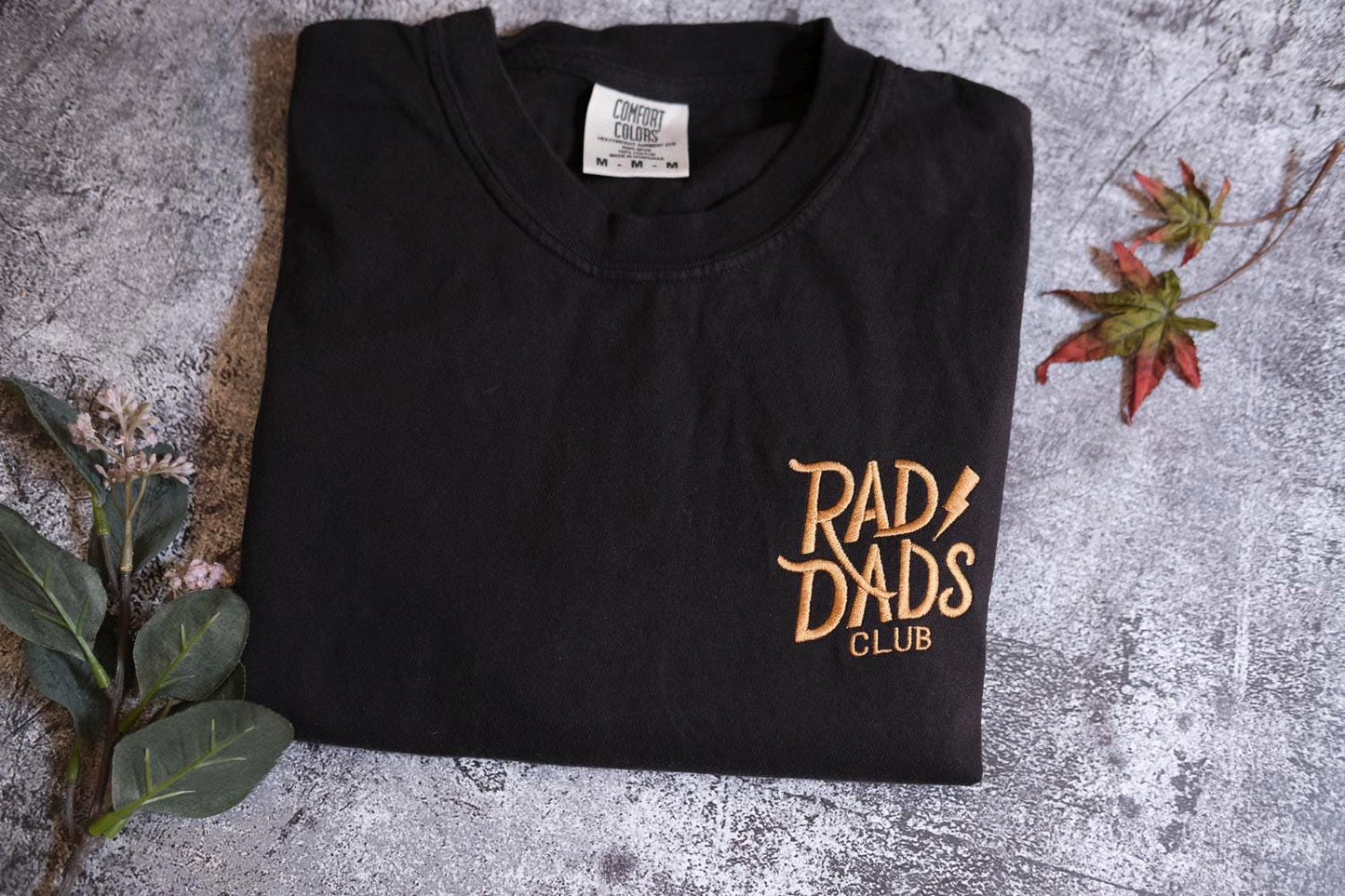 a black t - shirt with a rad of dads club logo on it