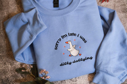 A light blue sweatshirt with a humorous text and graphic design printed on it.