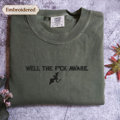 a green t-shirt with the text "WELL THE F*CK AWARE" printed on it.