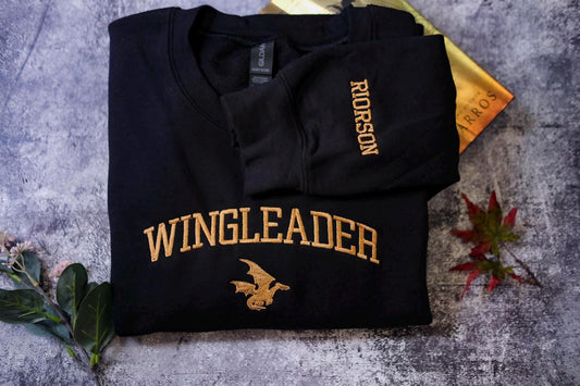 a black shirt with a gold wingleader on it