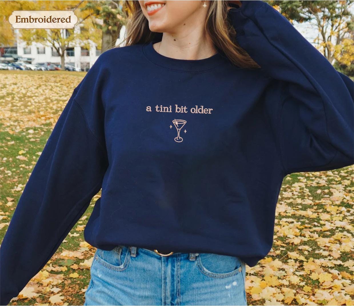 a woman wearing a blue sweatshirt with a wine glass on it