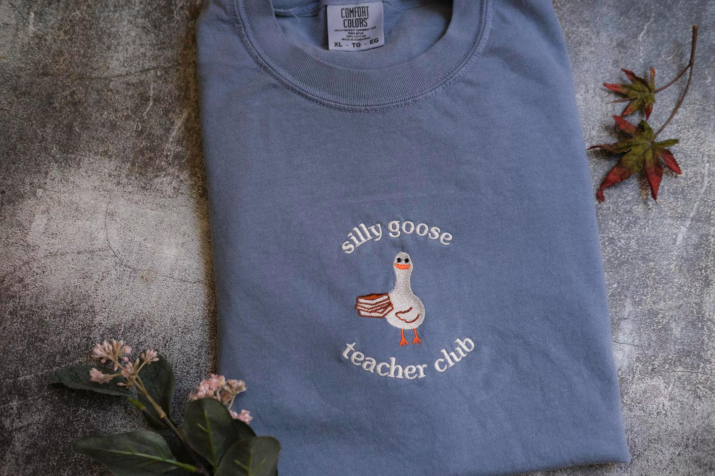 a blue t - shirt with a duck embroidered on it