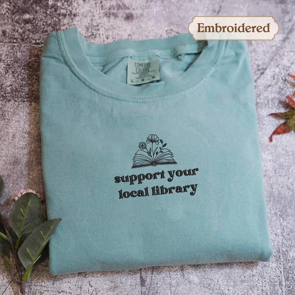 A light blue t-shirt with a printed message on it, placed on a textured surface.