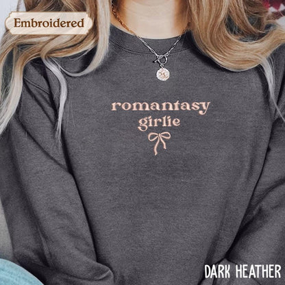 A close-up of a person wearing a gray sweatshirt with the text &quot;romantic girl lie&quot; embroidered on it.