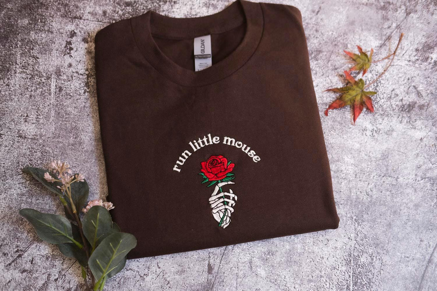 a brown t - shirt with a rose on it