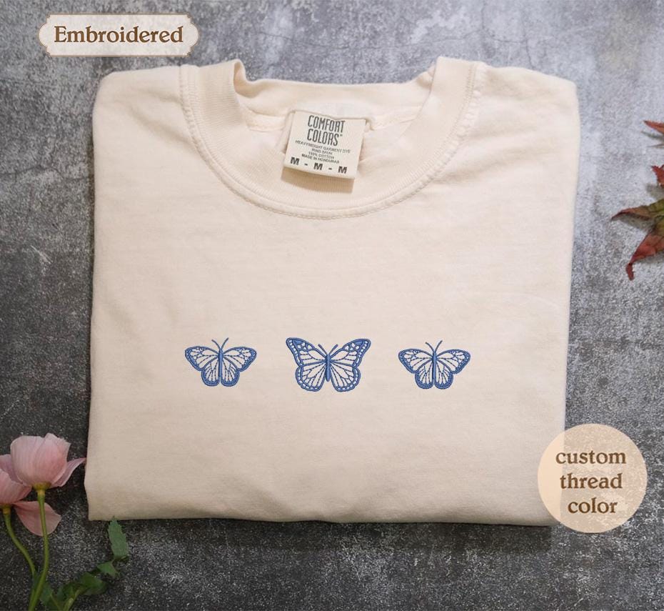 a white t - shirt with three blue butterflies on it